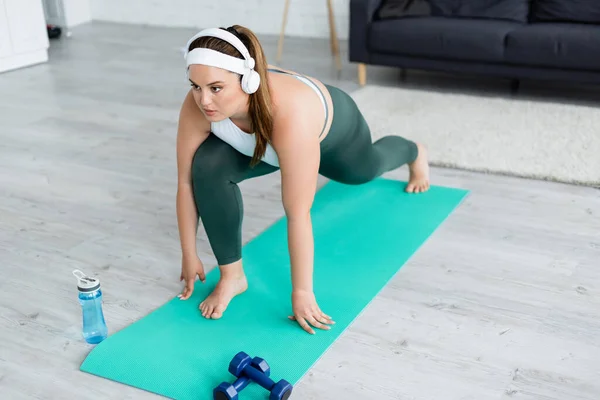 Deportiva Talla Grande Auriculares Entrenando Colchoneta Fitness Cerca Botellas Deportivas — Foto de Stock