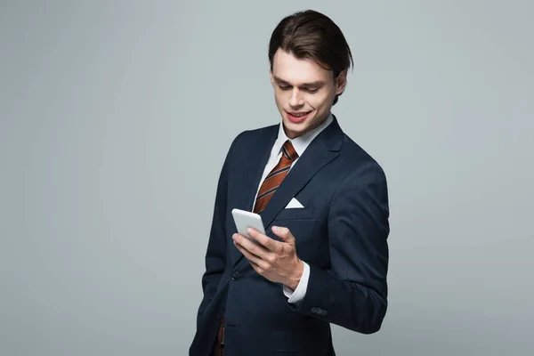 Χαρούμενο Νεαρό Επιχειρηματία Κοστούμι Χρησιμοποιώντας Smartphone Απομονωμένο Γκρι — Φωτογραφία Αρχείου