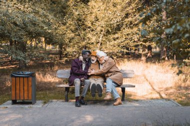 Parkta kürsüde birbirine sarılan pozitif ırklar arası yaşlı adamlar. 