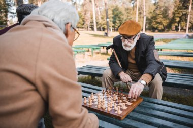 Sonbahar parkında bankta satranç oynayan yaşlı adamlar 