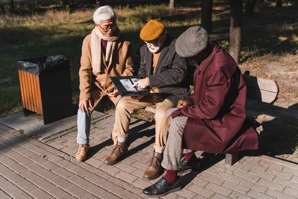 Senior Man Wijst Naar Foto Album Buurt Van Interraciale Vrienden — Stockfoto