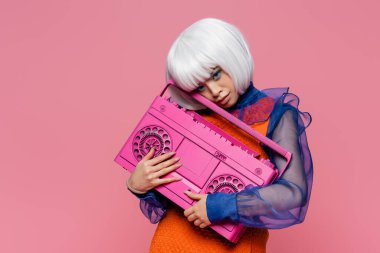 Beyaz peruklu güzel bir Asyalı kadın pembe bir teyp tutuyor. 