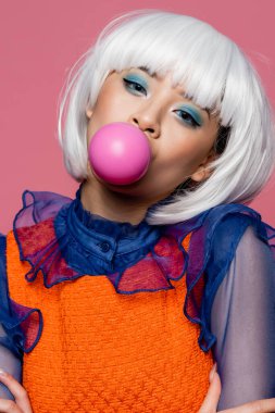 Popüler sanat tarzında Asyalı bir model pembe üzerine sakız üflüyor. 