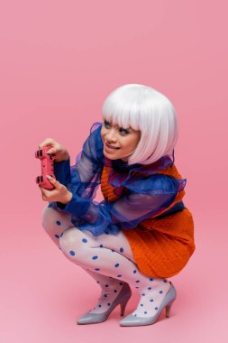 KYIV, UKRAINE - 10 Aralık 2020: Pembe arka planda oynayan gülümseyen Asyalı pop sanat modeli