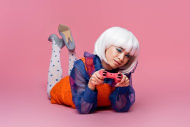 KYIV, UKRAINE - 10 Aralık 2020: Pembe arka planda joystick tutan beyaz peruklu Asyalı pop sanatçısı kadın