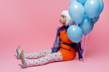 Pembe arka planda mavi balonlar tutan şık Asyalı pop sanat modeli