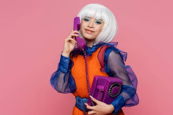 积极的亚洲流行艺术模型在电话上交谈 看着用粉色隔离的相机 — 图库照片
