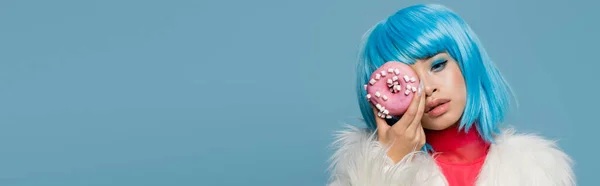 花哨的亚洲女人拿着带釉面的甜甜圈 脸被蓝色的横幅隔开 — 图库照片