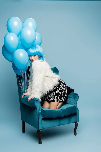 Smiling Asian Pop Art Model Looking Camera Balloons Armchair Blue — Stock Photo, Image