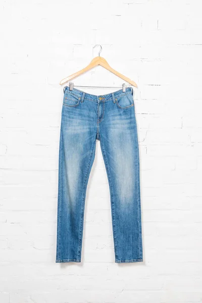 Синие джинсы на вешалке возле стены из белого кирпича — стоковое фото