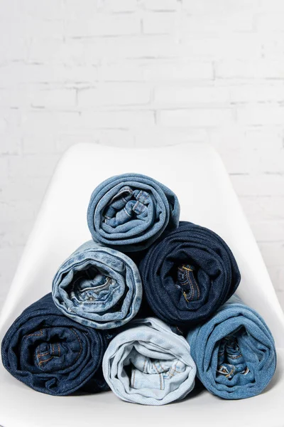 Close up view of rolled jeans on white chair near brick wall — Stock Photo