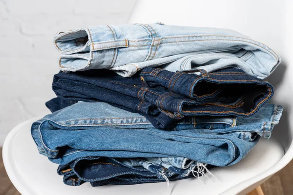 Close up view of various jeans stacked on chair — Stock Photo