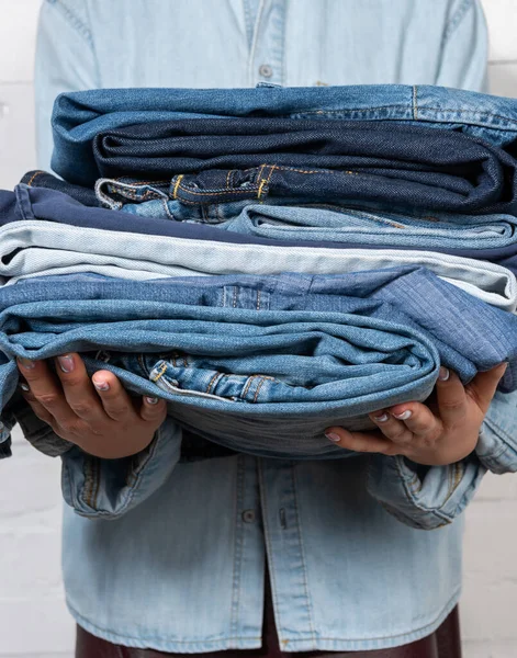 Vue partielle de la femme tenant des vêtements en denim empilés — Photo de stock