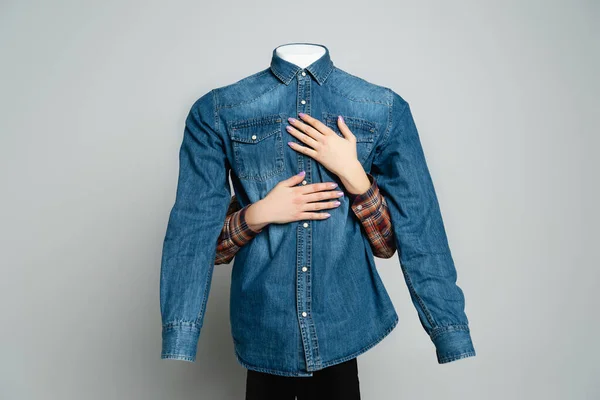 Cropped view of woman embracing mannequin in blue denim shirt on grey — Stock Photo