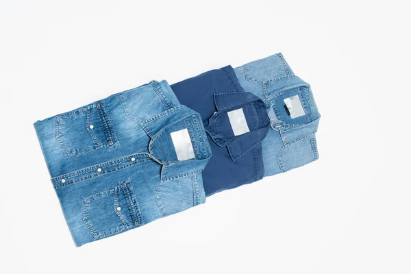 Draufsicht auf verschiedene blaue Jeanshemden auf weißem Hintergrund — Stockfoto