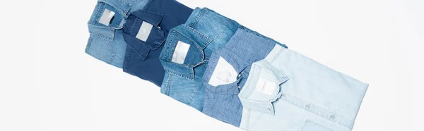 Diagonal row of different denim shirts on white background, top view, banner — Stock Photo