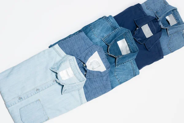 Vue de dessus de différentes chemises en denim sur fond blanc — Photo de stock