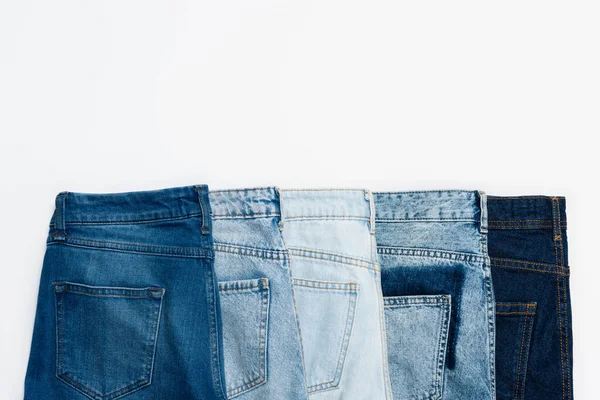 Horizontale Reihe verschiedener blauer Jeans isoliert auf weißem Grund, Ansicht von oben — Stockfoto