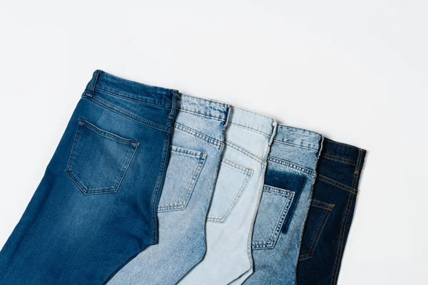 Flat lay of different blue jeans on white background, top view — Stock Photo