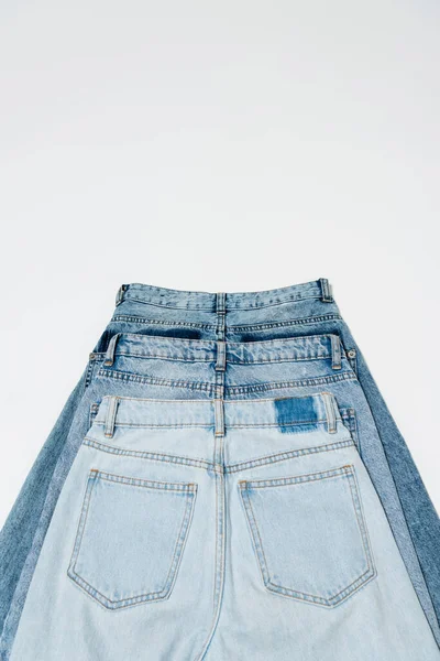 Плоская укладка различных джинсов на белом фоне, вид сверху — стоковое фото