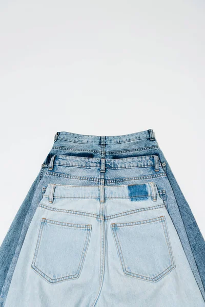 Pose plate de différents jeans sur fond blanc, vue de dessus — Photo de stock