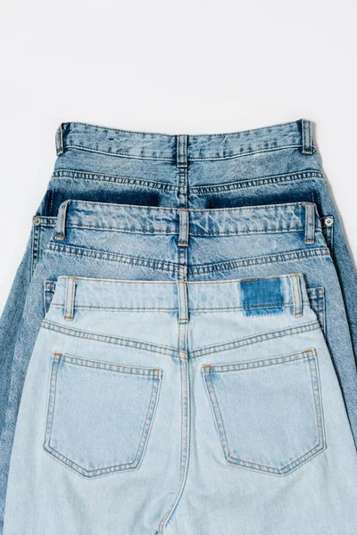 Vue de dessus de différents jeans bleus sur fond blanc — Photo de stock