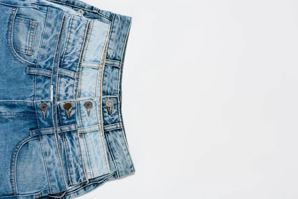 Jeans blu diversi su sfondo bianco, vista dall'alto — Foto stock