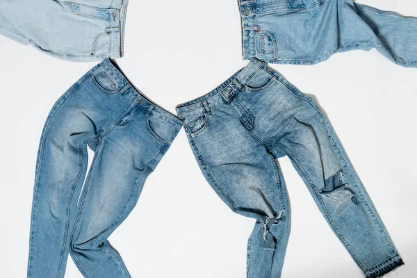 Vista dall'alto di vari jeans in denim su sfondo bianco — Foto stock