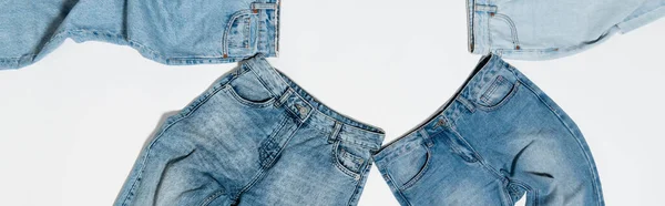 Vista superior de diferentes pantalones vaqueros azules sobre fondo blanco, bandera - foto de stock