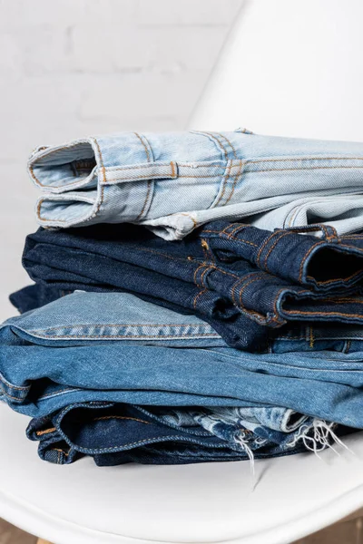 Close up view of blue jeans stacked on white chair — Stock Photo