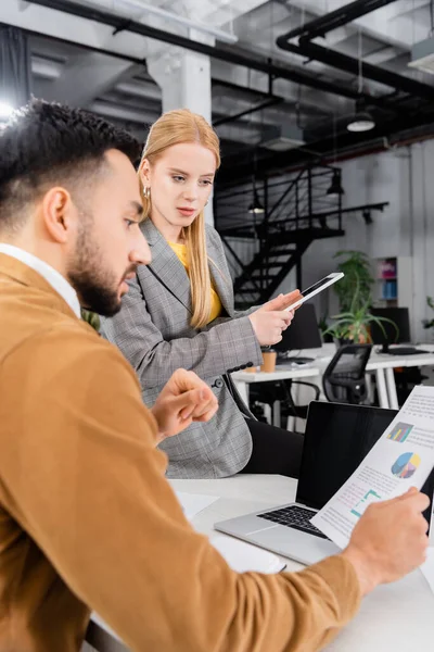 Businesswoman holding digital tablet near arabian businessman with document on blurred foreground — Stock Photo