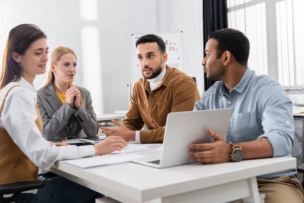 Multikulturelle Geschäftsleute sitzen im Büro neben Laptop — Stockfoto