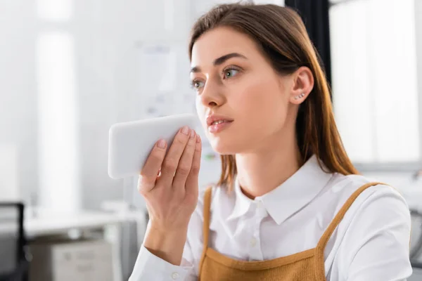 Smartphone in hand of young businesswoman in office — Stock Photo