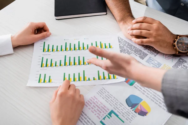 Cropped view of business people working with graphs on papers near notebook on table — Stock Photo