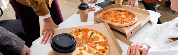 Обрезанный вид деловых людей рядом с пиццей и напитком на вынос в офисе, баннер — стоковое фото