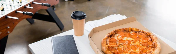 Notebook, coffee to go and tasty pizza on table in office, banner — Stock Photo