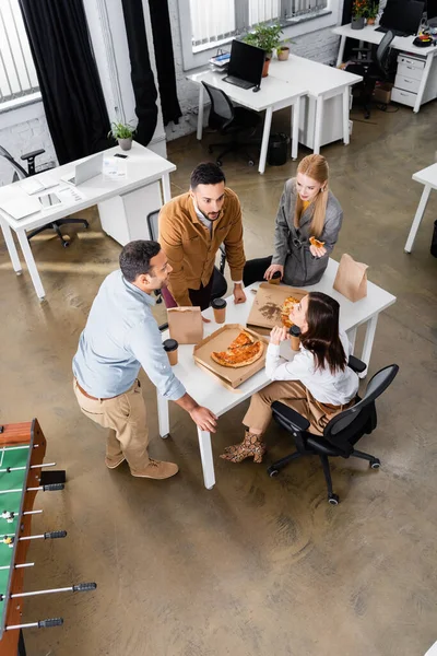 Обзор межрасовых деловых людей, разговаривающих во время обеда в офисе — стоковое фото