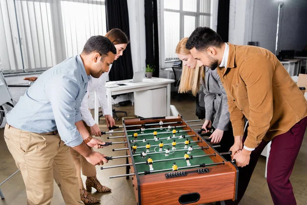 Interrassische Geschäftsleute spielen im Büro gemeinsam Tischkicker — Stockfoto