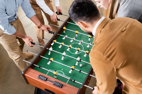 Overhead view of business people playing table soccer with colleagues in office — Stock Photo