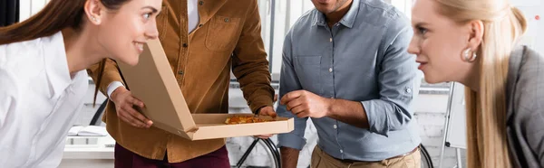 Geschäftsleute halten Pizza in der Nähe von Geschäftsfrauen auf verschwommenem Vordergrund im Büro, Banner — Stockfoto