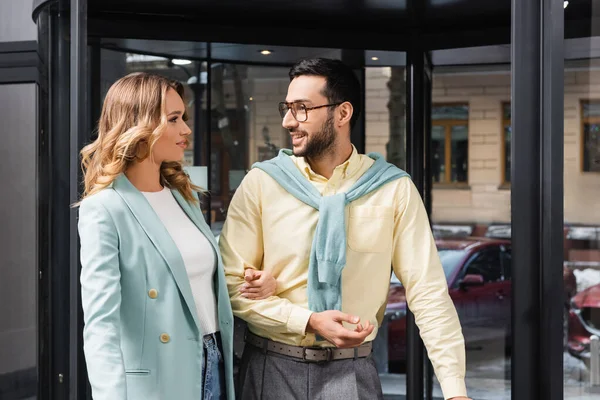 Hombre musulmán sonriente hablando con su novia cerca de la puerta en el hotel - foto de stock