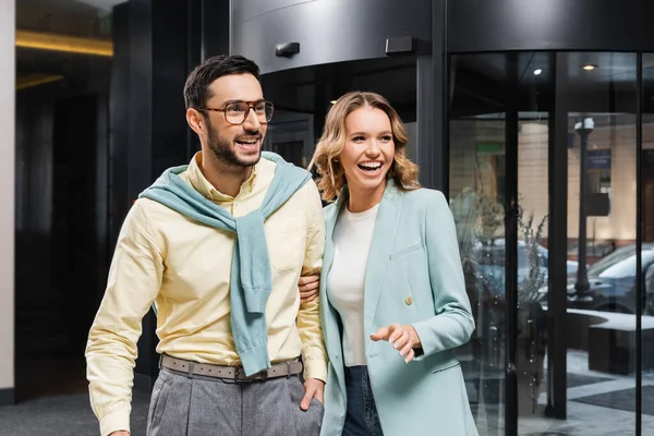 Cheerful interracial couple looking away near hotel — Stock Photo