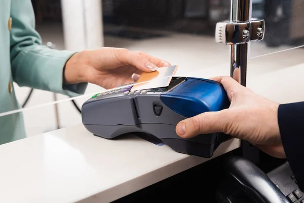 Cropped view of hotel receptionist with payment terminal and woman with credit card in hotel lobby — Stock Photo