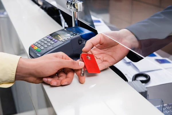 Cropped view of hotel manager giving key to man in lobby — Stock Photo