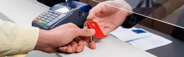 Cropped view of hotel manager giving key to man in lobby, banner — Stock Photo