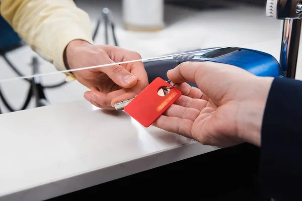 Vista recortada de la recepcionista del hotel dando la llave al hombre — Stock Photo