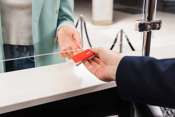 Cropped view of hotel manager giving key to woman in lobby — Stock Photo