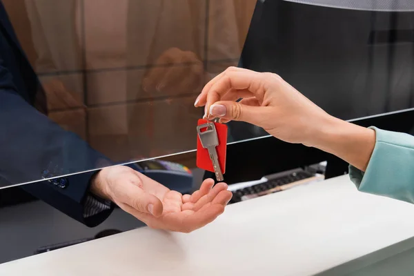 Cropped view of woman holding key near hand of manager in hotel — Stock Photo