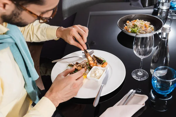 Muslim man sitting near tasty shrimps and water on table in hotel room — Stock Photo