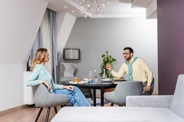 Casal interracial conversando durante jantar saboroso no quarto de hotel — Fotografia de Stock